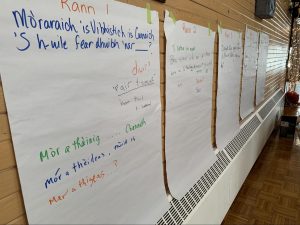 Flip chart paper on the wall with handwritten Gaelic texts in varied colours.