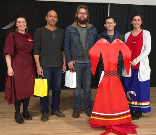 Five students standing in a row displaying the four-foot-tall steel red dress as a part of the second annual Tribute to Missing and Murdered Indigenous Women, Girls and Two-Spirited people.