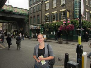 A young woman on a European street carries a map and a camera.