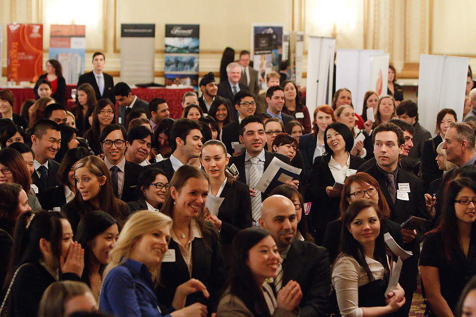 A crowd of students dressed in business clothes. Many hold folders.