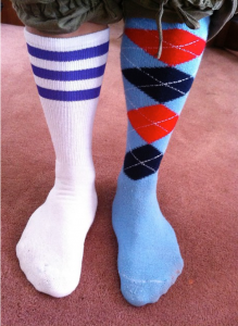 Person wearing one sock with stripes and one with diamond pattern