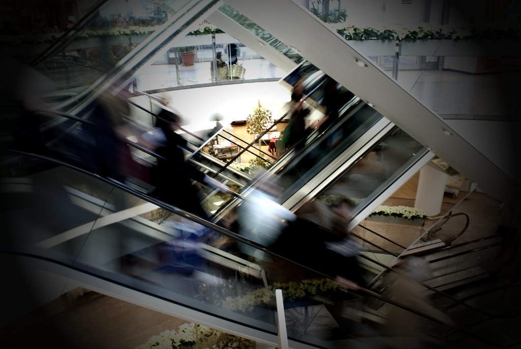 Picture of busy people using escalators in a mall.