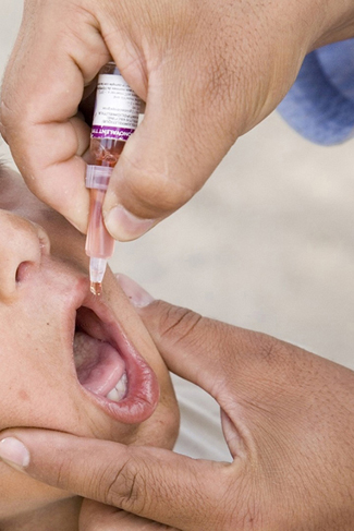 A photograph shows a child being given an oral vaccine.
