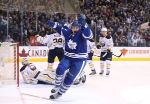 A photograph showing Zach Hyman of the Toronto Maple Leafs, with arms raised in celebration after scoring his first goal in a game against NHL team Buffalo Sabres.