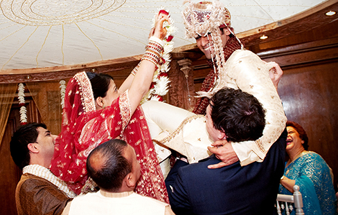 A photograph shows a bride and groom exchanging garlands in an Indian wedding ceremony.