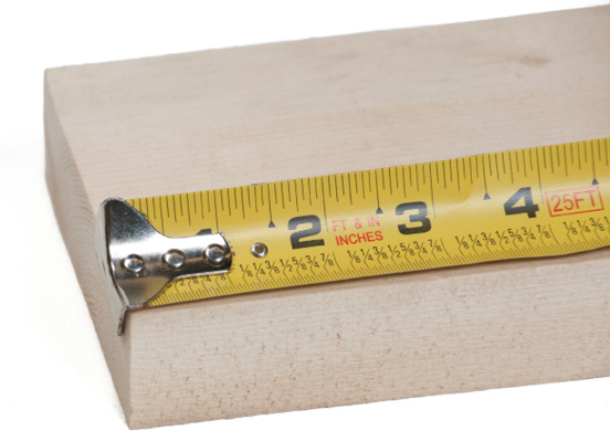 Tape measure with movable hook being used to measure a wooden block